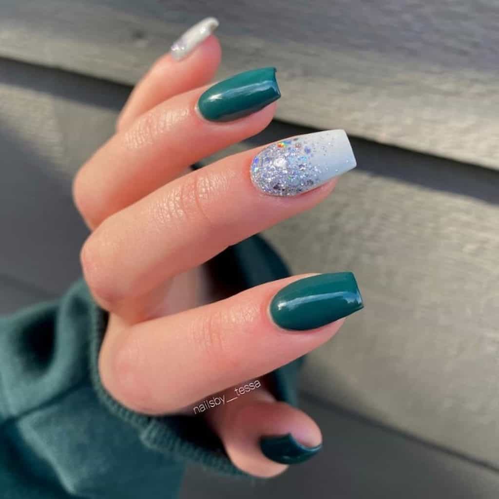 A closeup of a woman's hand with a combination of solid ocean green and pale blue-colored nails that has glitters