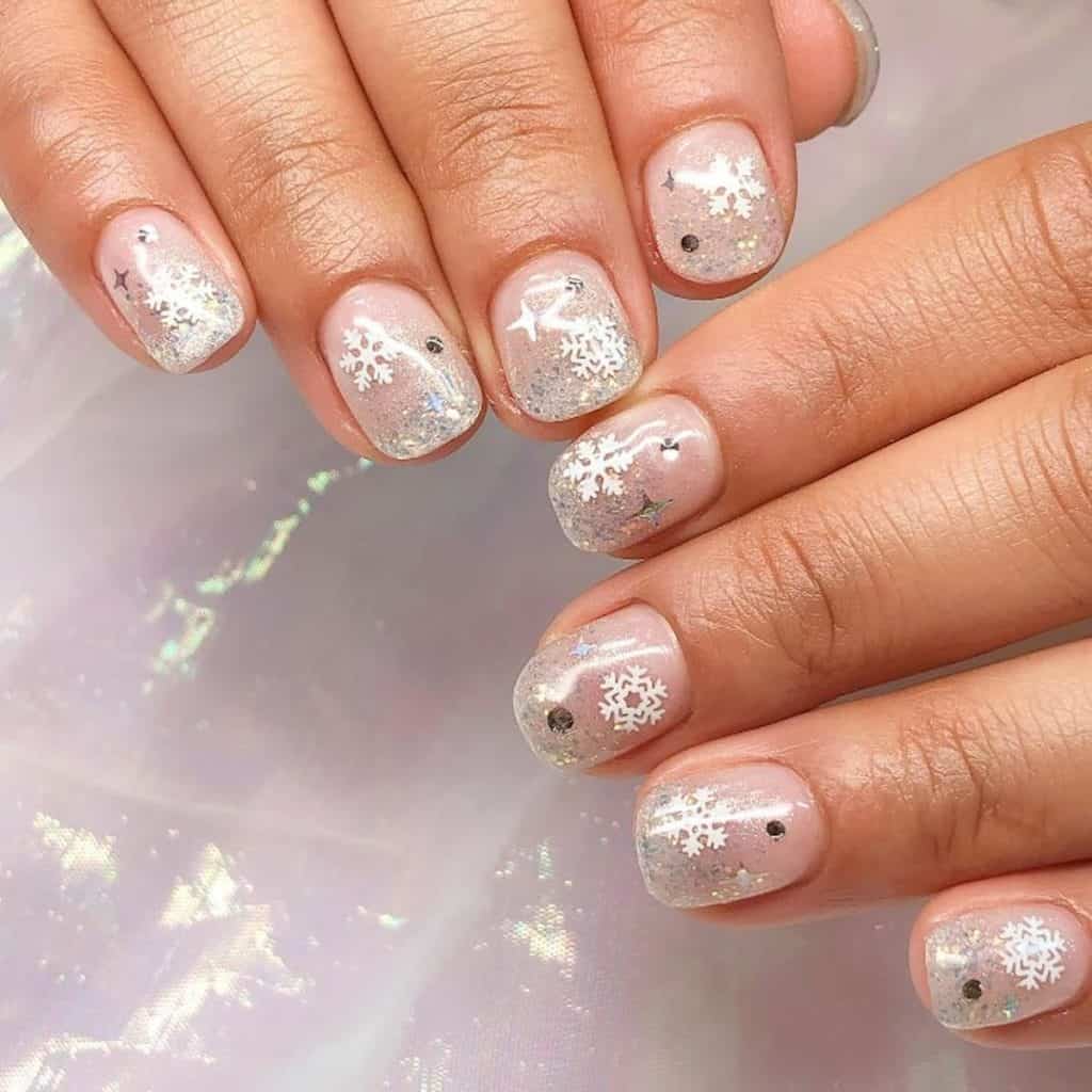 A closeup of a woman's hands with glitters and snowflakes nail designs