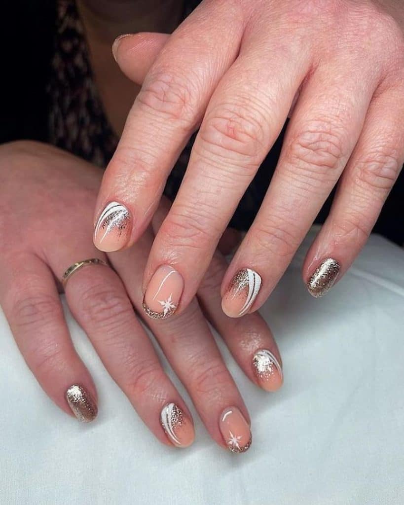 A closeup of a woman's hands with a nude nail polish that has gloss, glitter, and white nail art nail designs