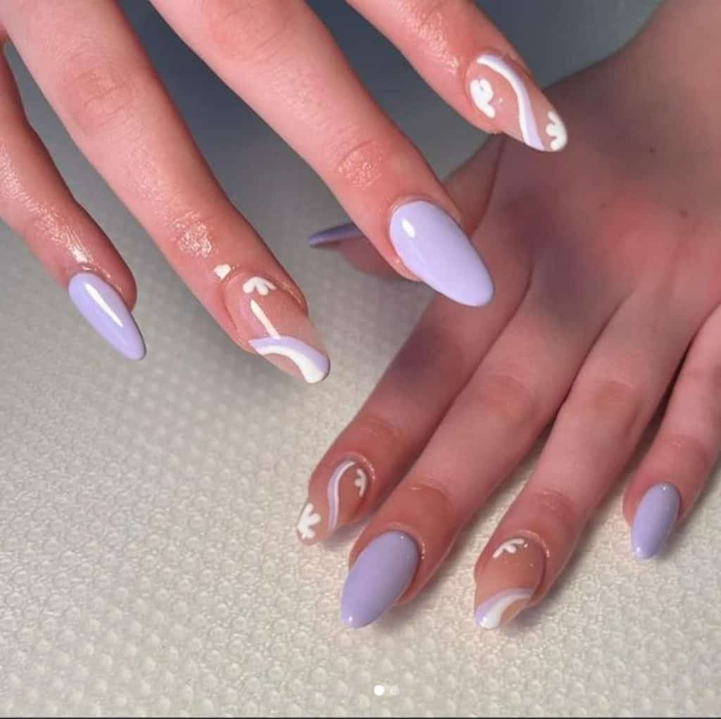 A woman's hands with lavender nail polish with white designs