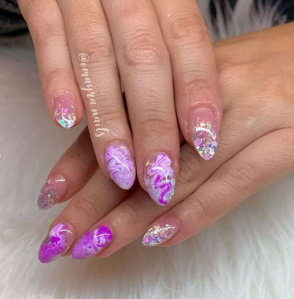 A woman's hands with a lavender nail polish with a mix of white and glitter designs 