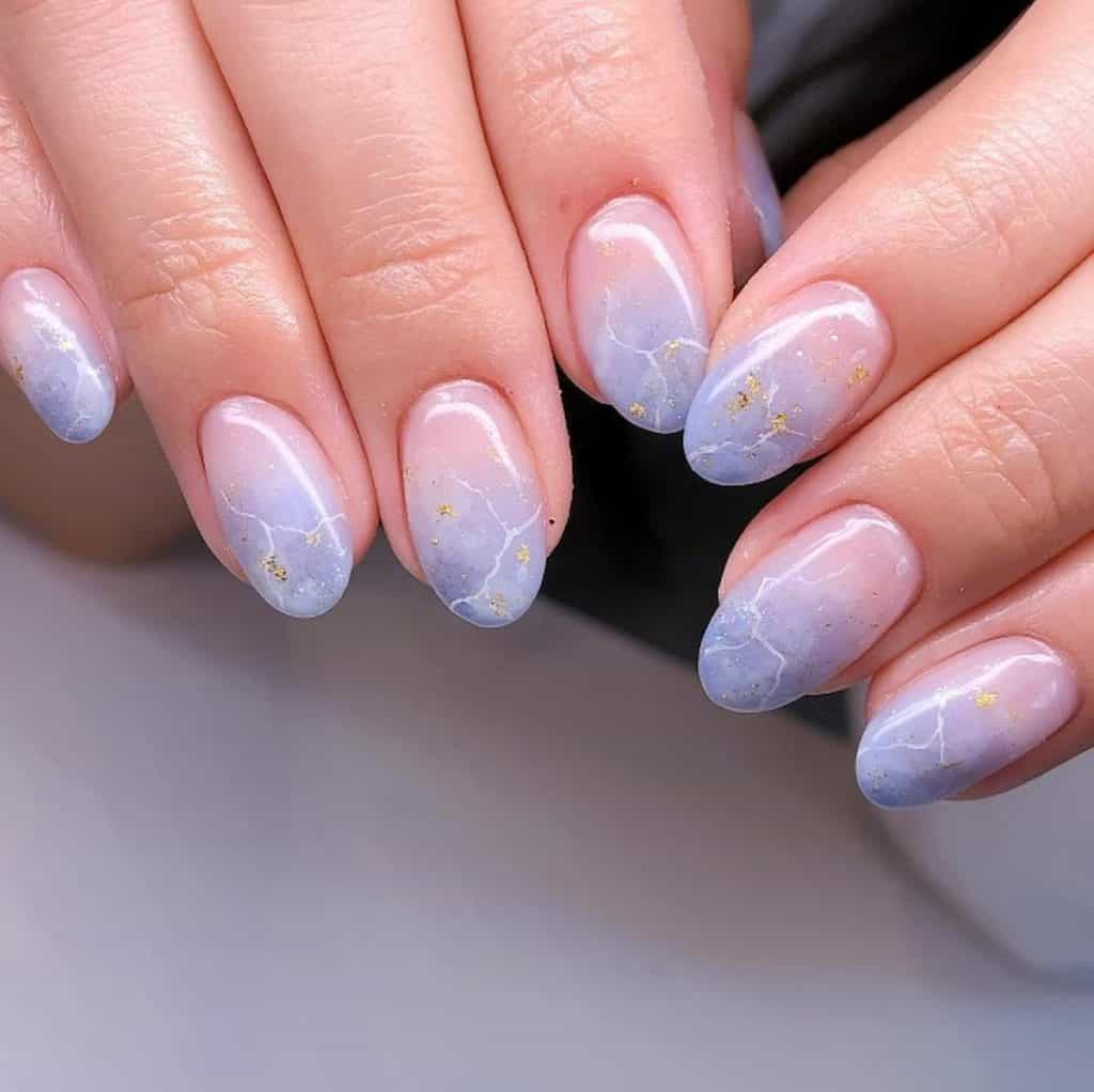 A woman's hands with ombre lavender nail polish with crack effects and gold flakes