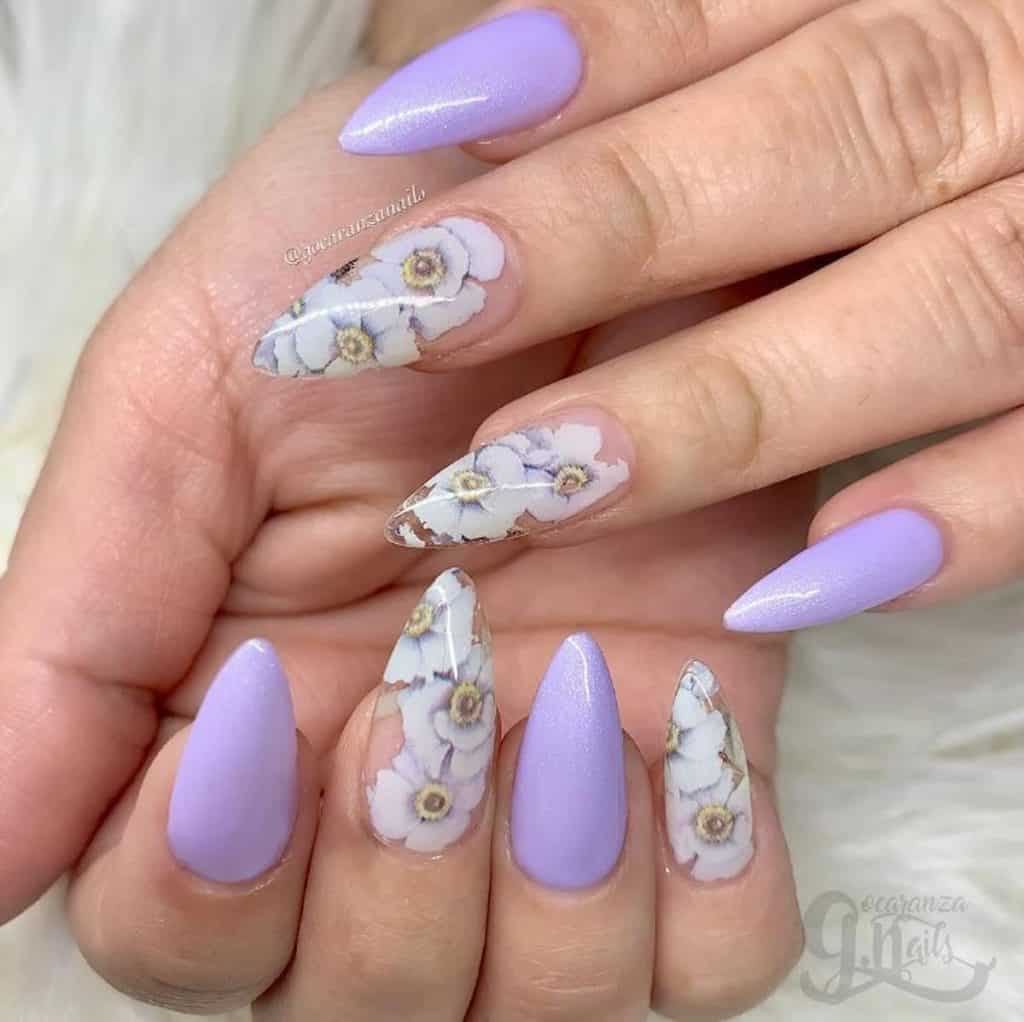 A woman's hands with long almond lavender manicure and white flowers design