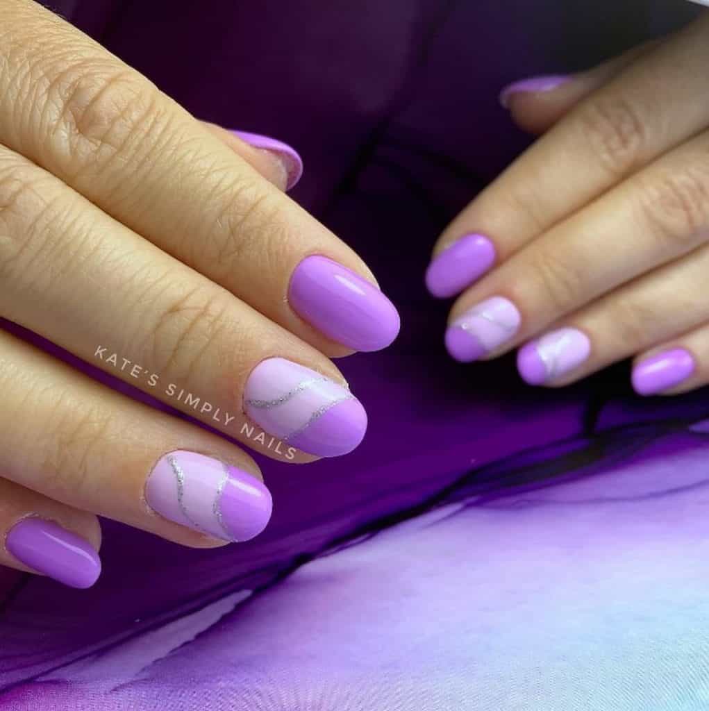 A woman's nails having a light and rich lavender colored nail polish with glittery silver waves design