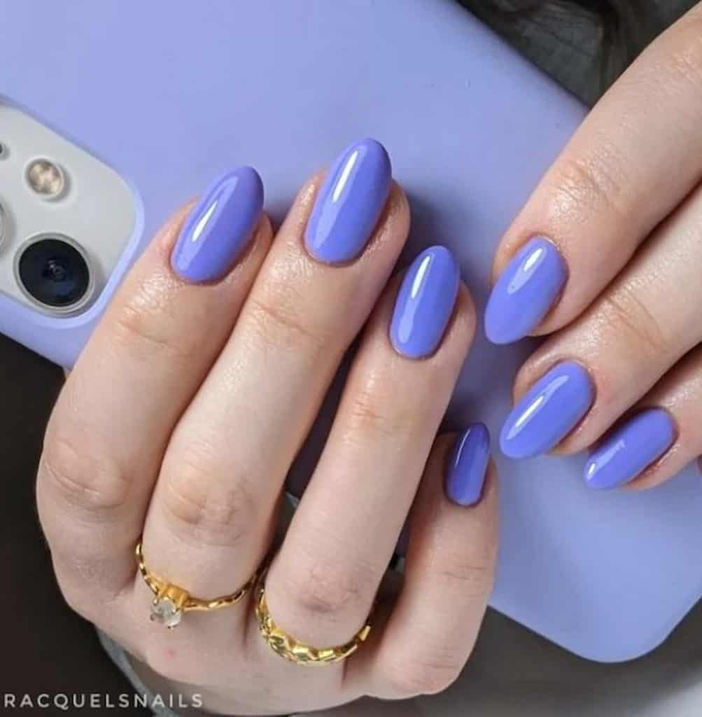 A woman's hands having blue toned lavender nail polish, holding her phone