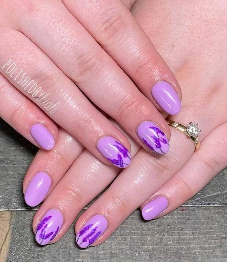 A woman's hands having lavender colored nail polish with lavender flower designs