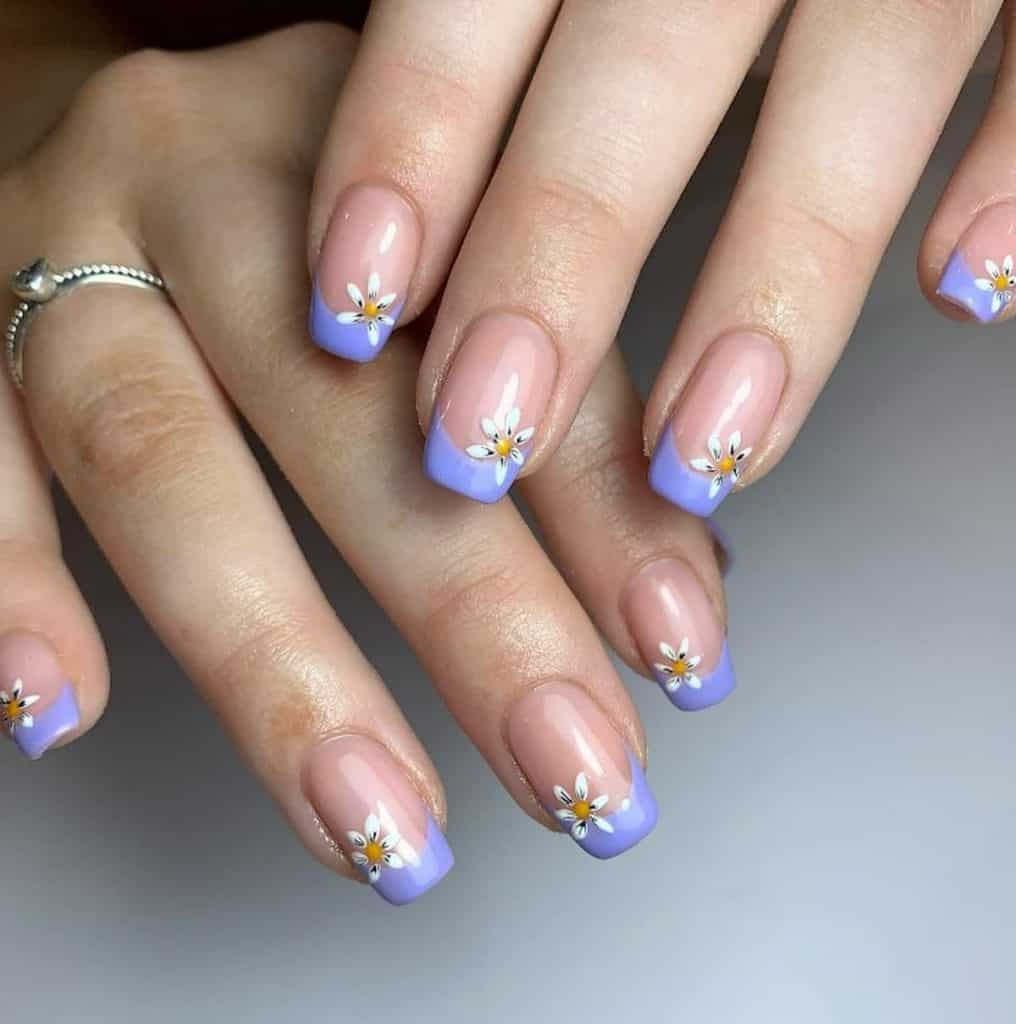 A woman's hands with nude nail polish, lavender colored tips, and lovely flower designs