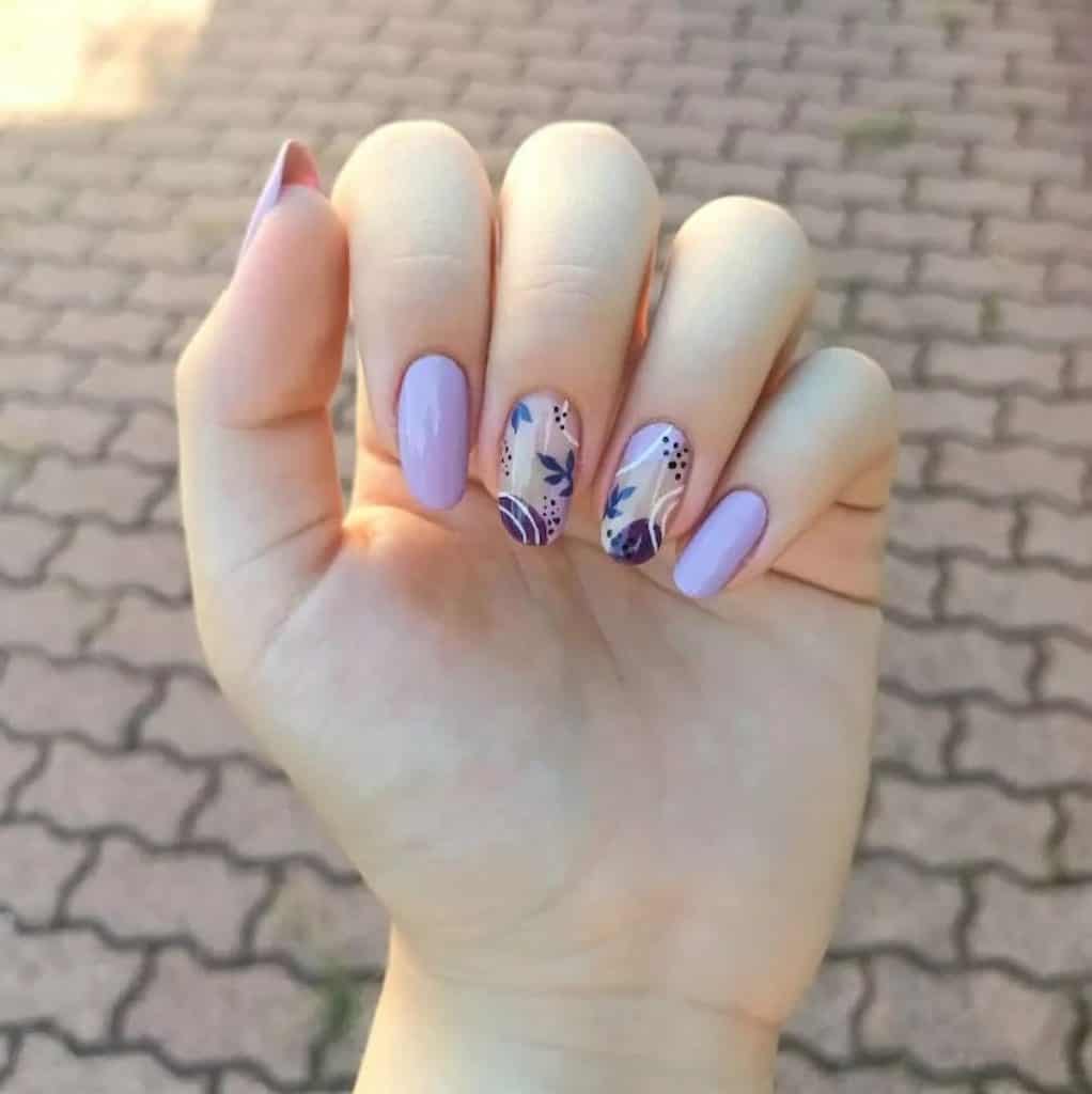 A woman's hand with a lavender colored nails and gray floral nail art