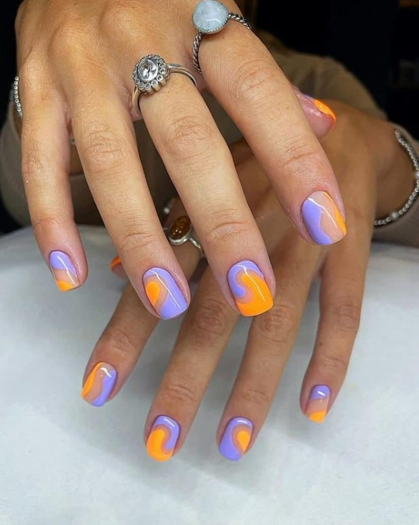 A woman's hands with lavender nail polish and bright orange nail design