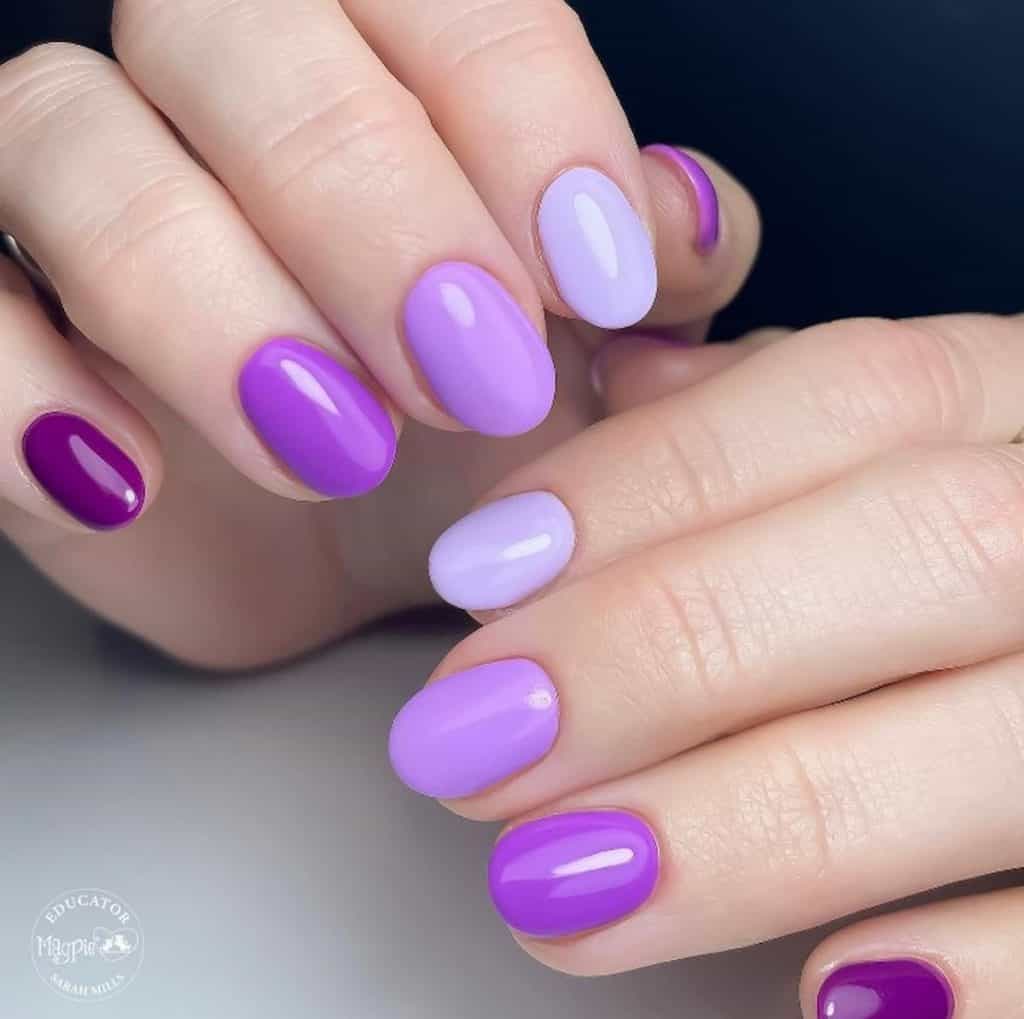A woman's hands with a combination of dark and light purple colored nails 