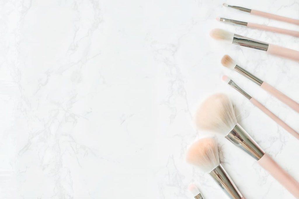 A group of makeup brushes on a marble surface.