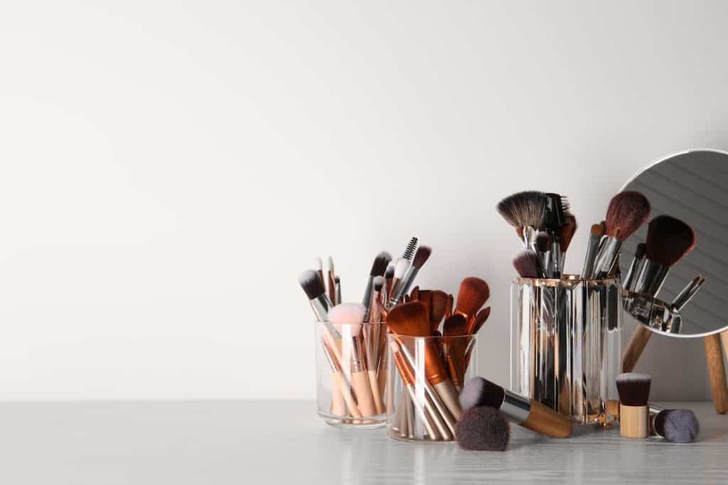 Complete set of professional makeup brushes on a table with a mirror.