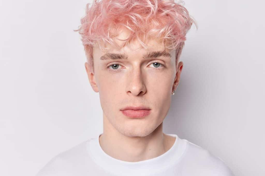 A young man with pink hair wearing white shirt isolated on a white background