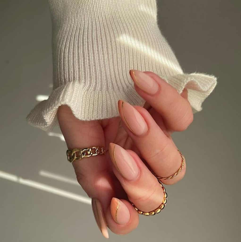 A closeup of a woman's hand with lighter peach base that has a lone gold streak