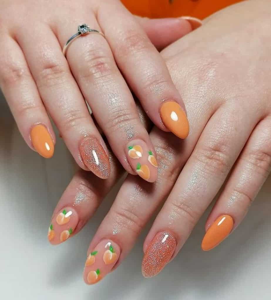 A closeup of a woman's hands with a combination of peach and orange colored nail polish that has peach fruits and silver glitter polish  