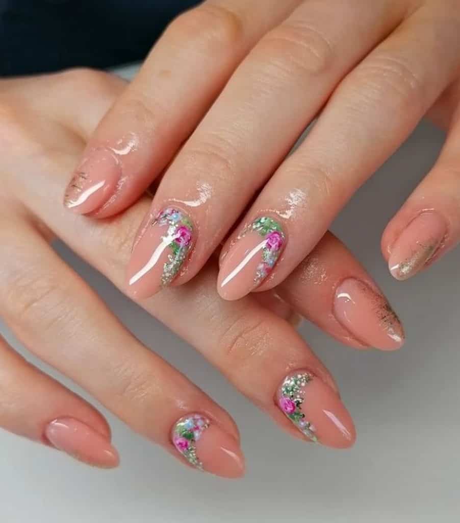 A closeup of a woman's hands with a peach nail polish that has floral garden and glitters as accents