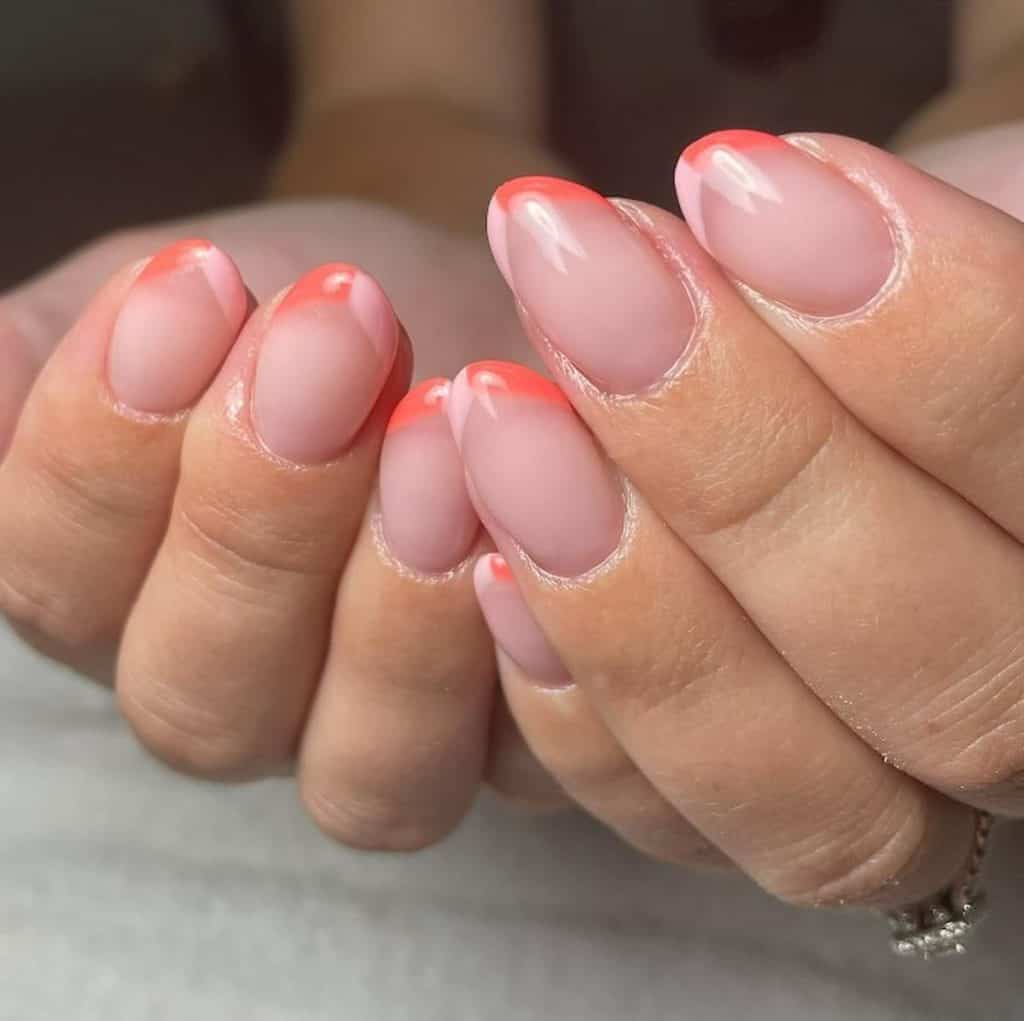 A closeup of a woman's hands with a sheer pink nail polish that has two toned French tips in pink and peach