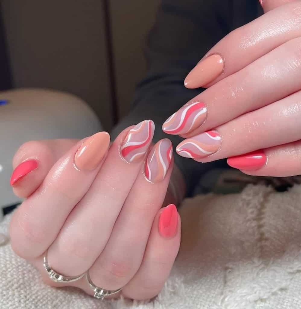 A woman's hands with beautiful with peach nail polish base that has peachy squiggly patterns on accent nails with a sheer white base