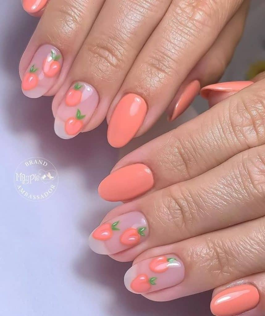 A closeup of a woman's hands with peach nail polish that has shiny hand-painted peach fruits nail designs on select nails