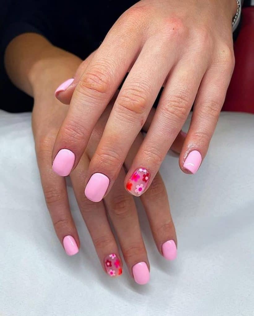 A woman's beautiful hands with pink nail polish that has beautiful accent floral nails in red, pink, and orange nail designs