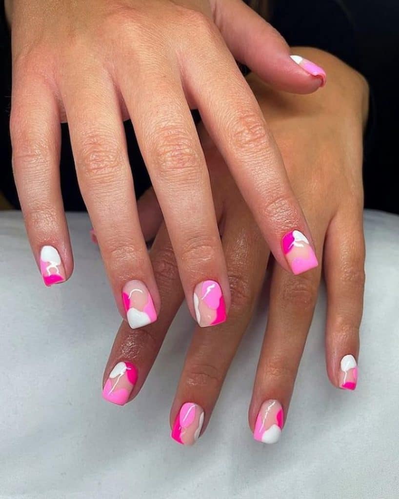 A woman's hands with a combination of white and pink nail polish that has a cotton candy patterns nail designs