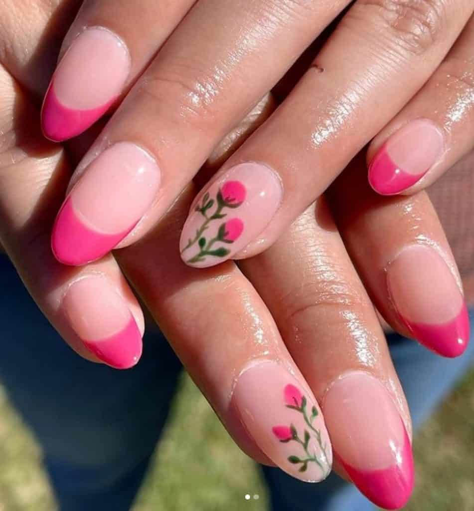 A closeup of a woman's hands with pink nail polish that has flowers and French tips nails designs