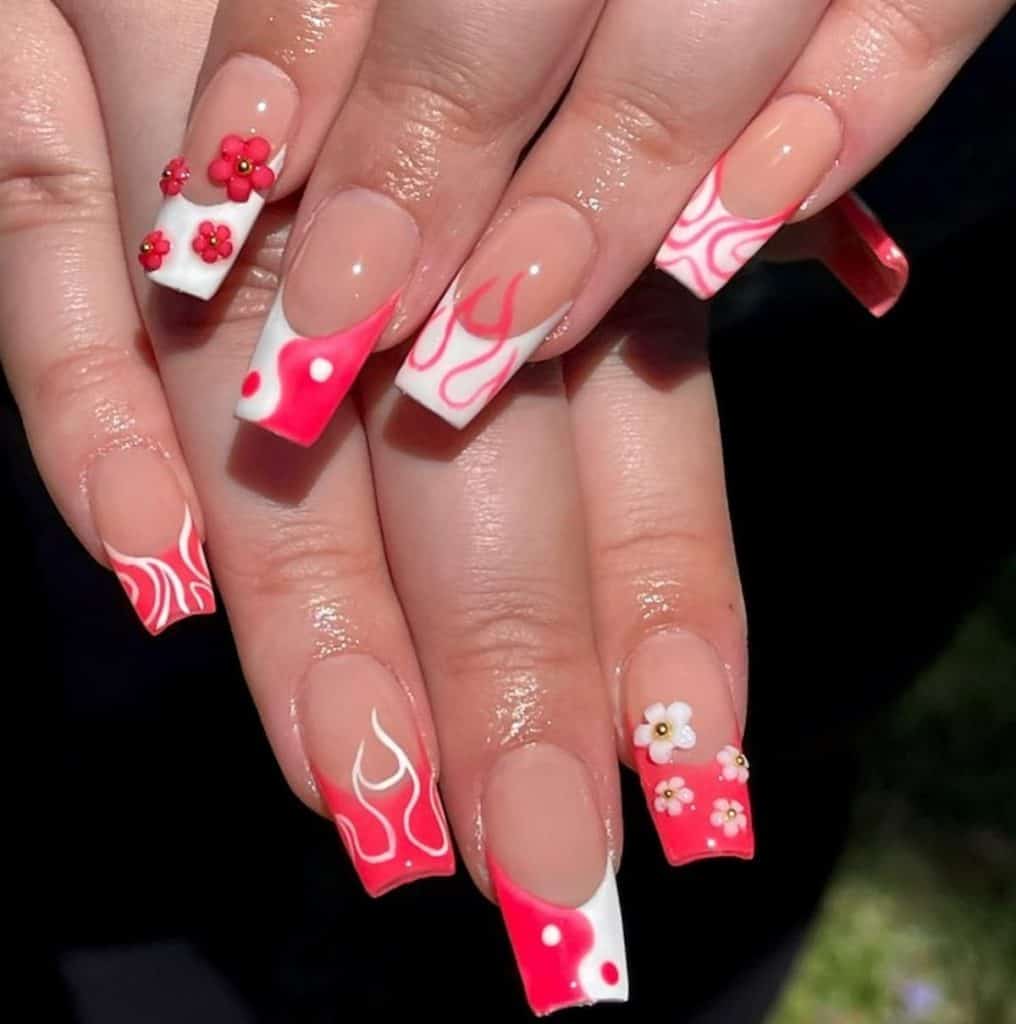 A closeup of a woman's hands with nude nail polish that has flames, yin yang, and 3D flowers nail designs