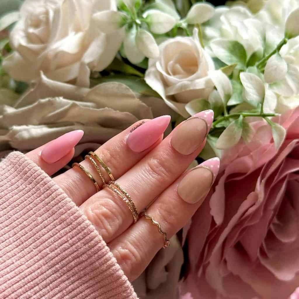 A woman's beautiful hand with a pink nail polish that has a gold colored accent and pink tips nail designs