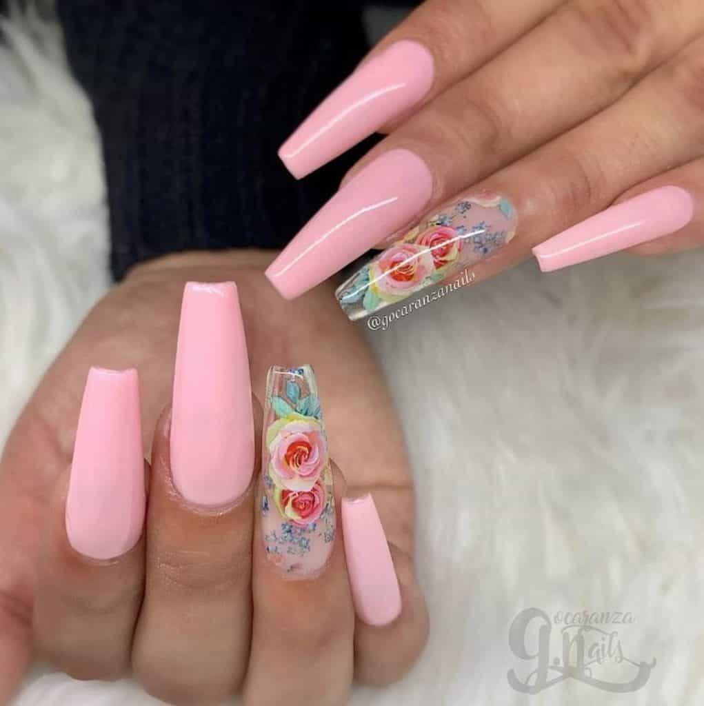 A woman's hands with pink nail polish that has roses in full bloom nail designs on select nails