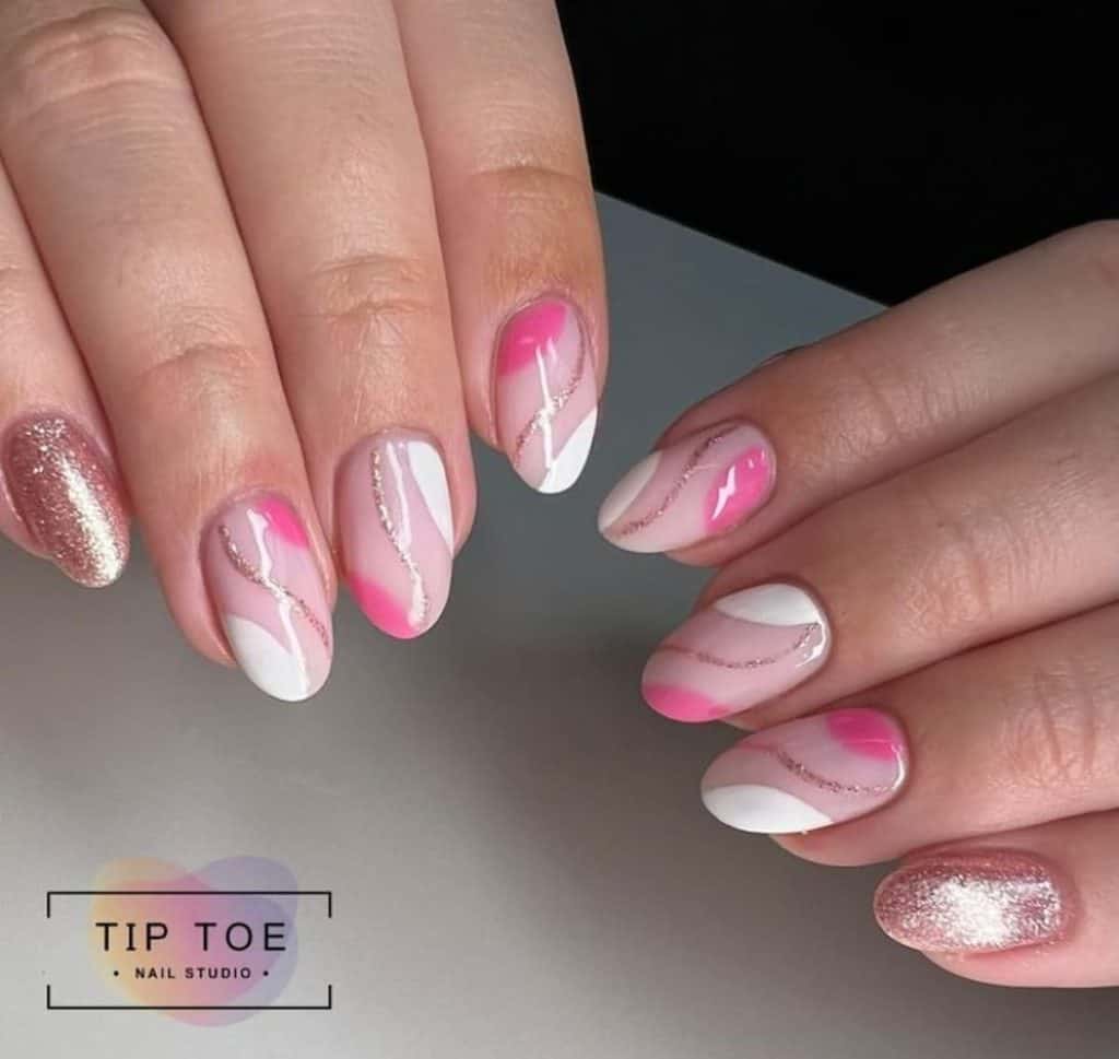 A woman's hands with a combination of white and pink nail designs that has glitters and sparkly streaks nail designs