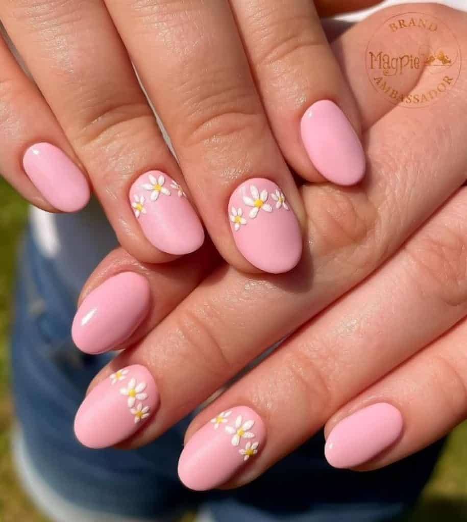 A closeup of a woman's hands with a beautiful pink nail polish that has tiny daisies nail designs