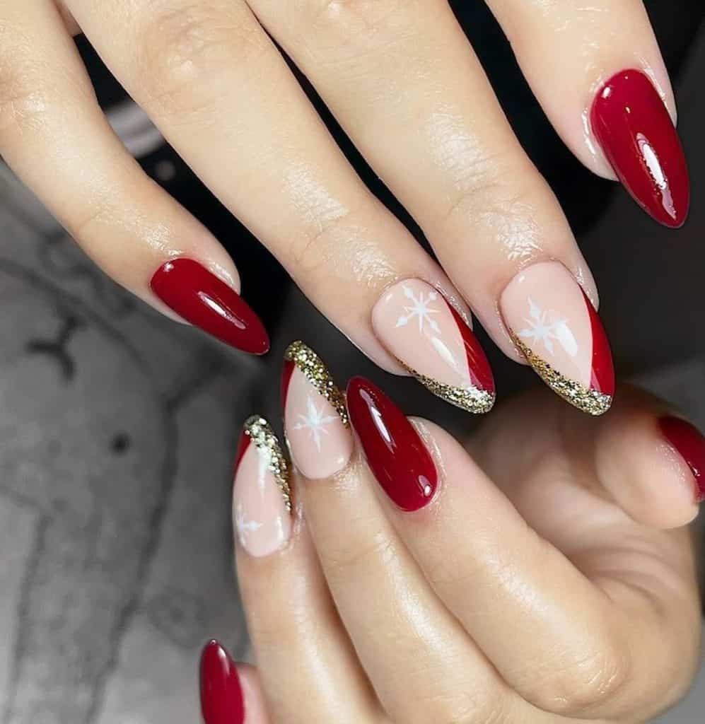 A closeup of a woman's hands with a combination of nude and red nail polish that has gold glitter polish for geometric French tips