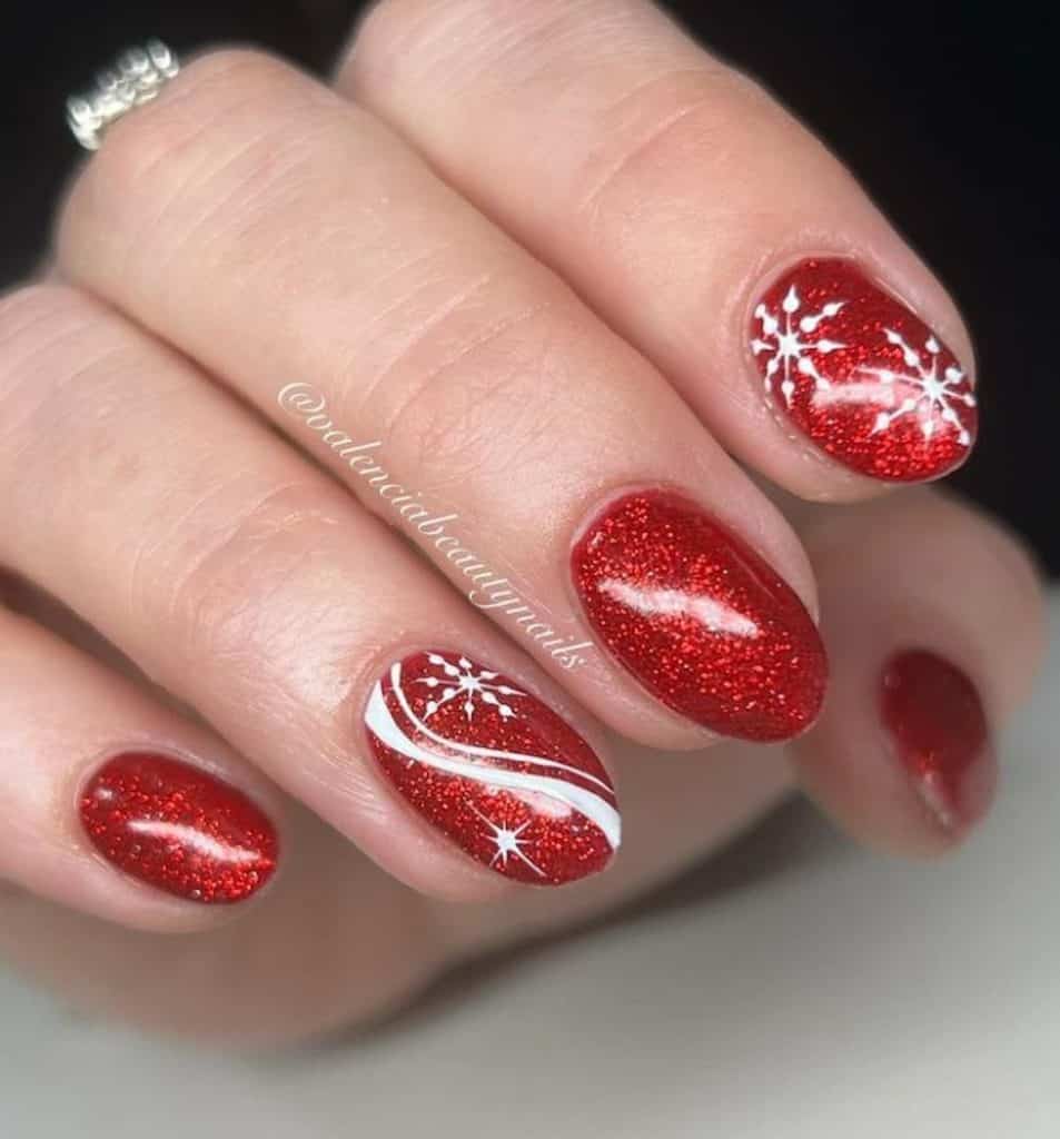 A closeup of a woman's hand with red nail polish base that has snowflake nail art on select nails