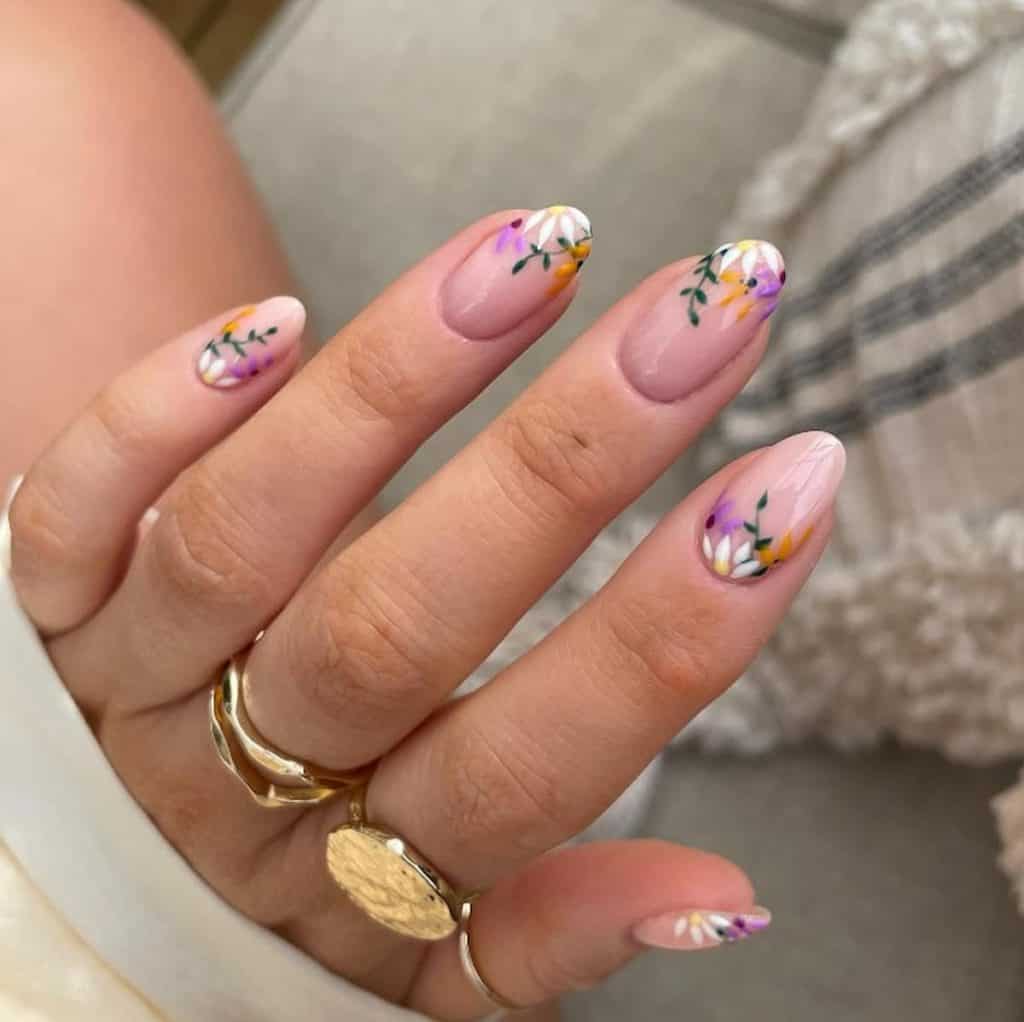 A closeup of a woman's hands with nude nail polish that has flower nail designs