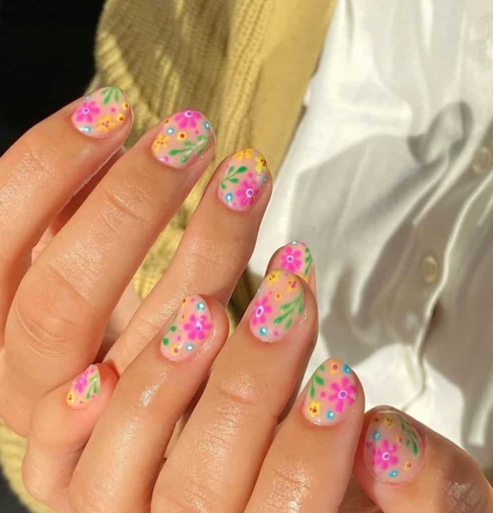 A closeup of a woman's hands with beautiful nude nail polish that has flowers and leaves nail designs
