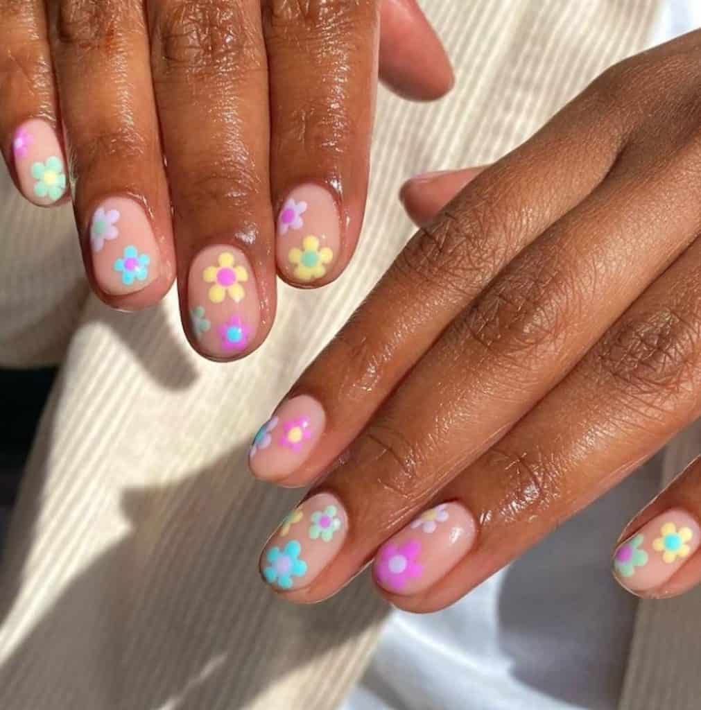A beautiful woman's hands with pinkish nude nail polish that has flowers nail designs