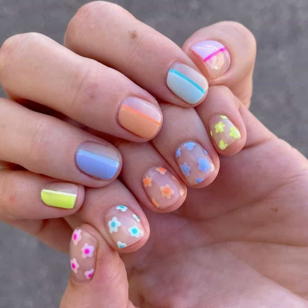A closeup of a woman's hands with multicolored nail polish that has flowers nail designs on select nails