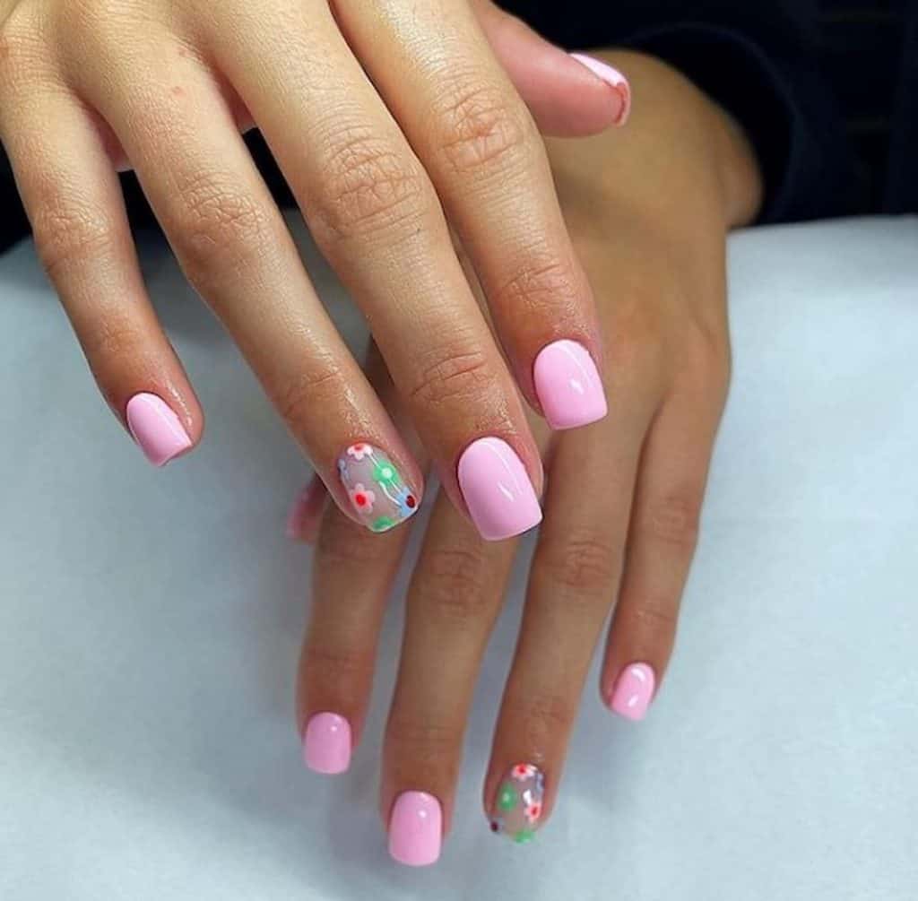A beautiful woman's hands with pink nail polish that has flowers nail design on select nails