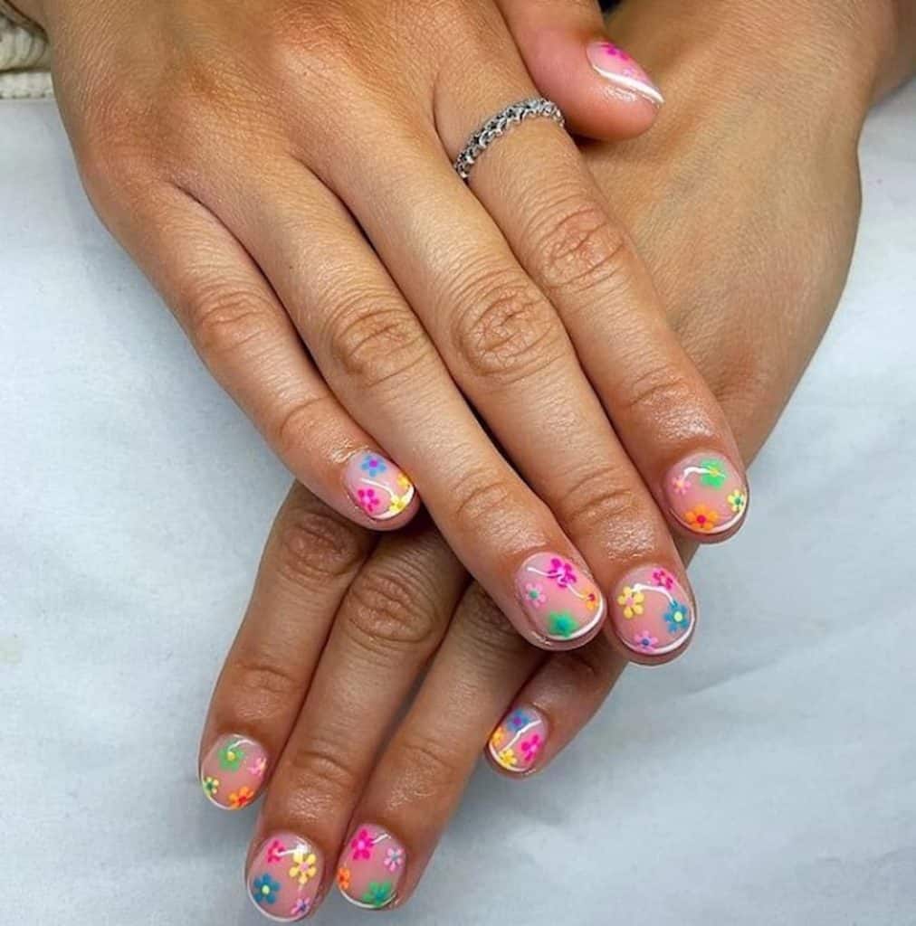 A beautiful woman's hands with nude nail polish that has colorful flowers nail designs 
