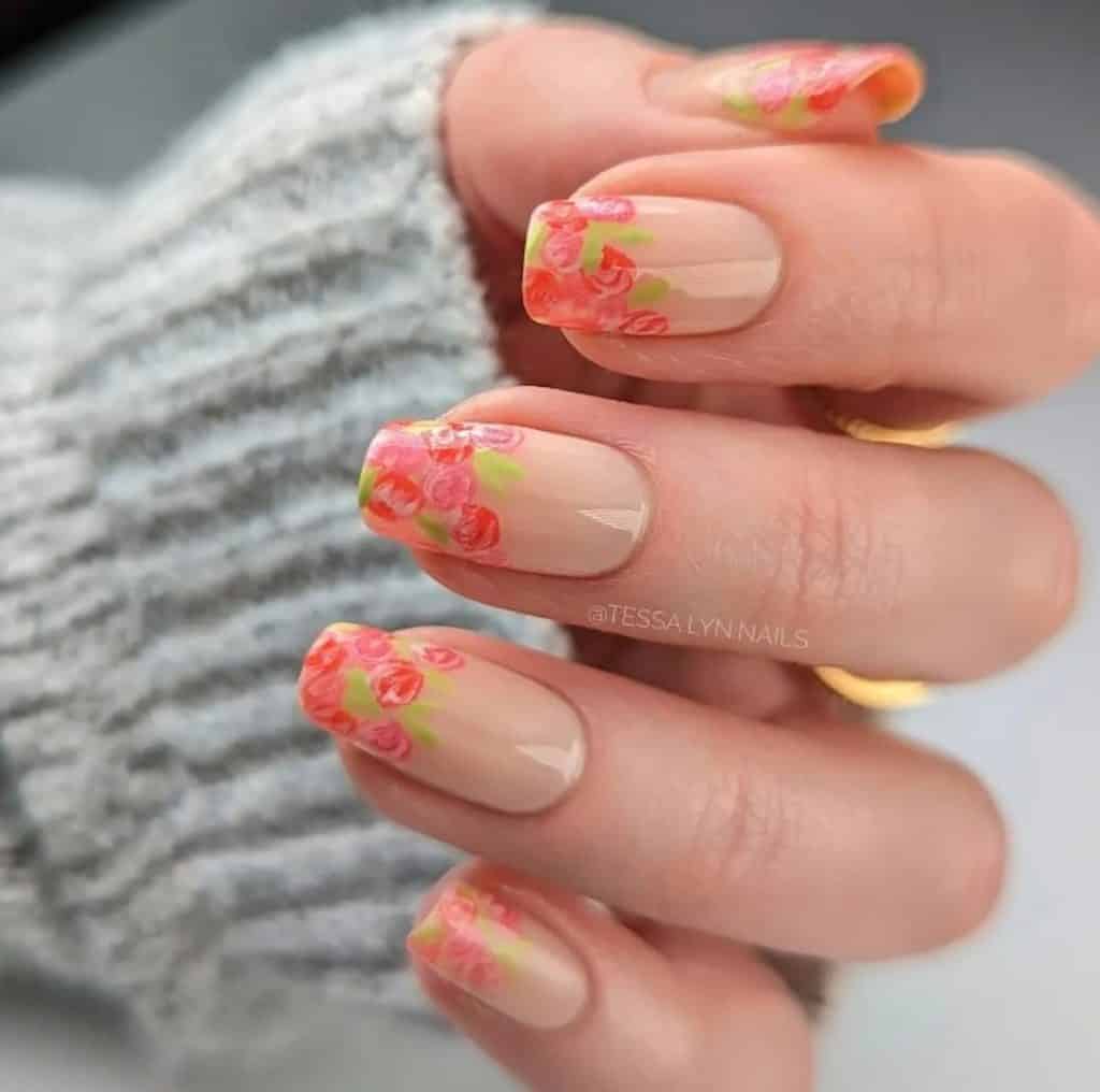 A closeup of a woman's hand with nude nail polish that has beautiful floral nail designs 