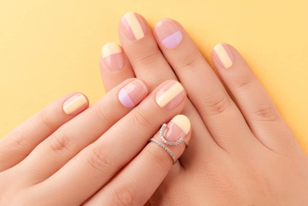 A woman's hands with beautiful nude nail polish and solid color blocks nail designs