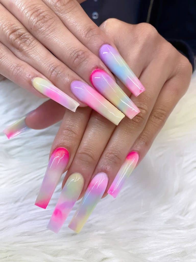 A woman's hands with long coffin acrylic nails and pastel yellow, purple, green, blue, and pink gradients