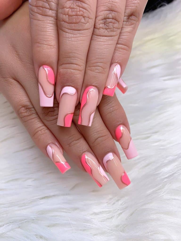A woman's hands with beautiful combination of different shades of pink nail polish and outline them with rose gold