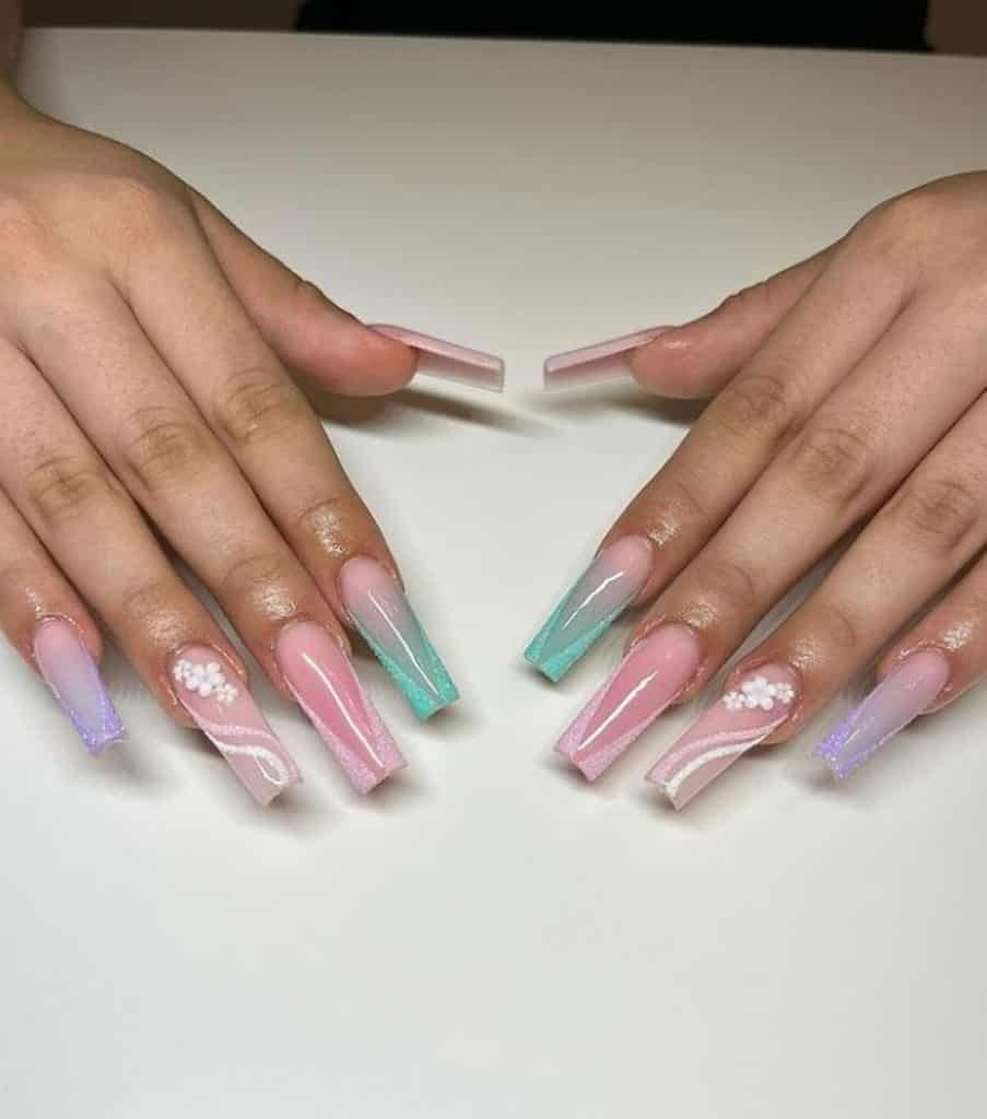 A woman's hands with a combination of nude, pink, green, and lavender nail polish that has 3D florals and streaks and borders, and white sugary glitters nail designs