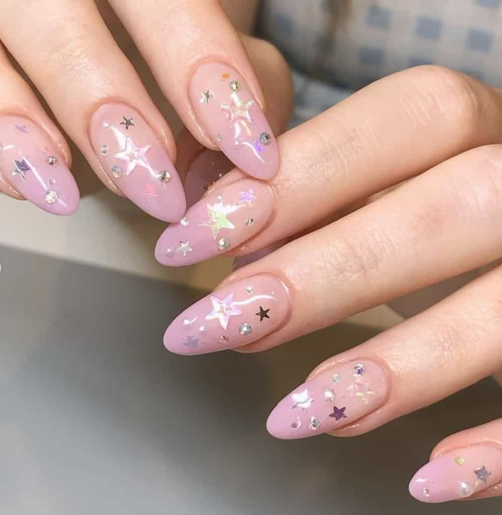 A closeup of a woman's hands with a pink almond nails that has 3D stars and studs nail designs