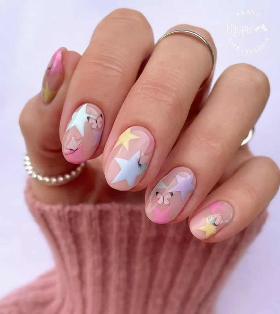 A closeup of a woman's hand with a nude nail polish that has pink butterflies nail designs