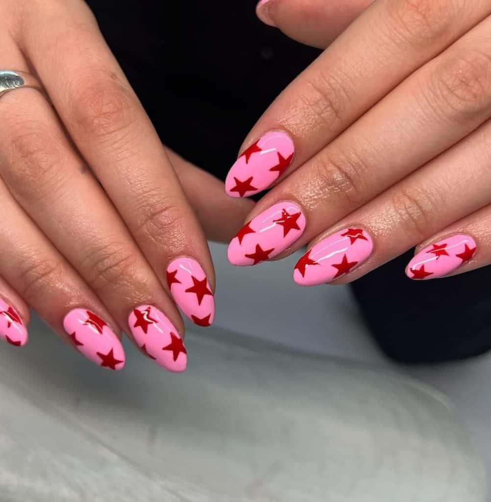A woman's hands with beautiful neon pink nail polish that has red stars nail designs