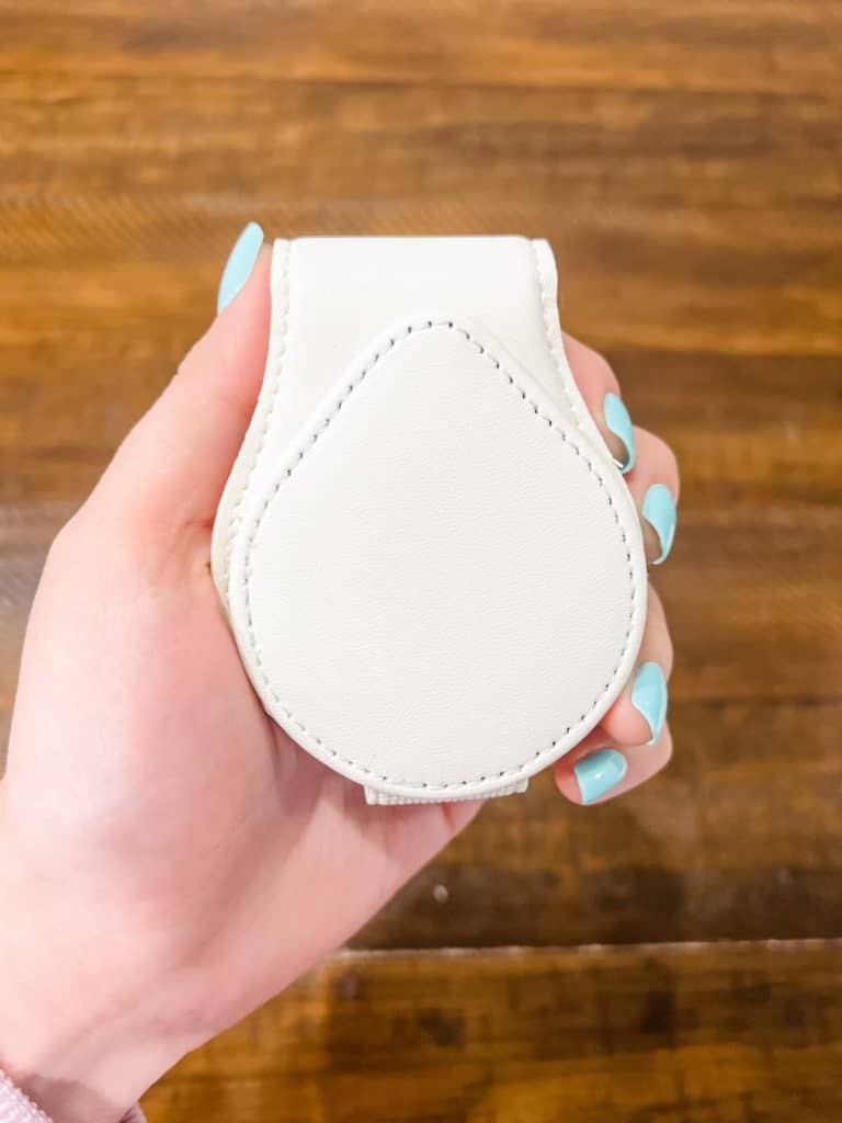 A hand holding a white faux leather sunglasses holder from Temu