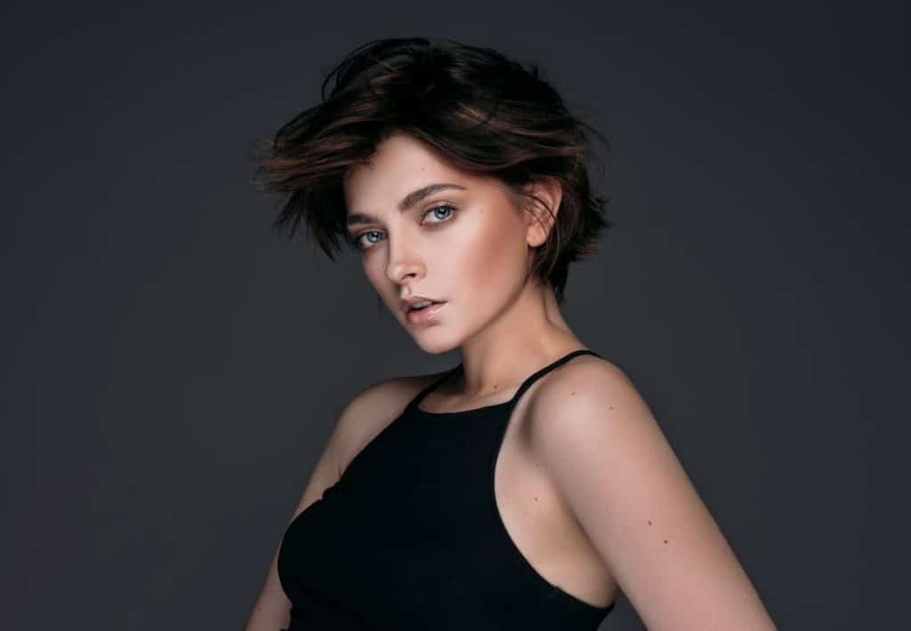A brunette woman with a pixie bob hair cut isolated on a black background