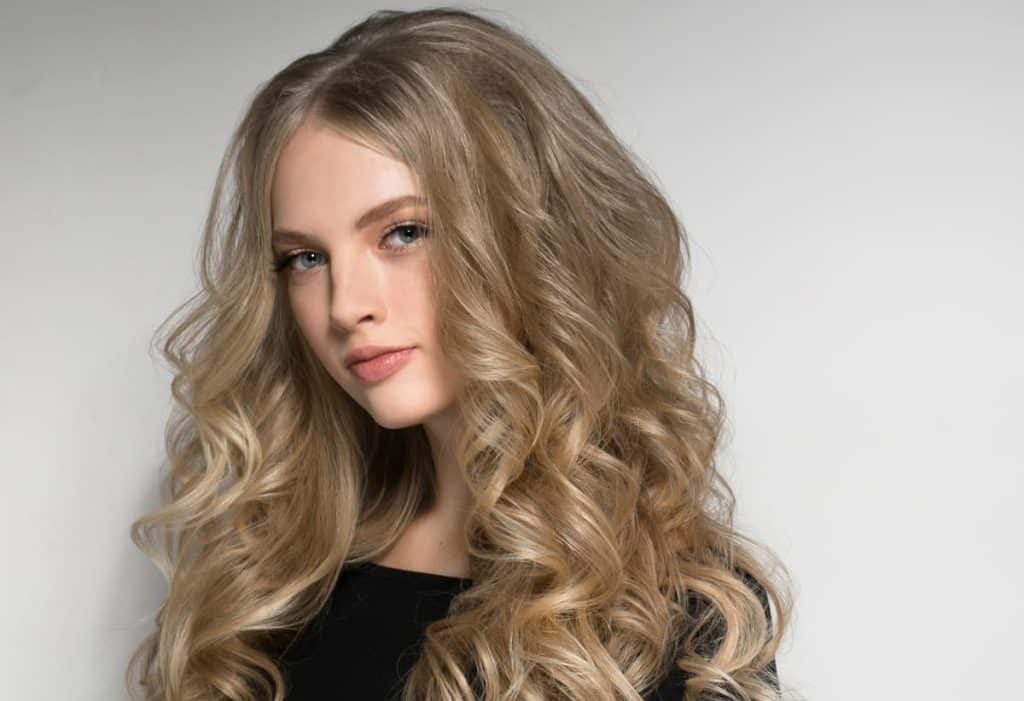 A beautiful young woman with long curly medium blonde hair and brown lowlights
